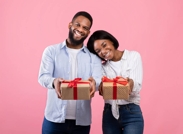 Portrait of Valentine sweethearts with gift boxes celebrating holiday together on pink studio background - Photo, Image