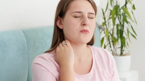Portret młodej brunetki womnan masującej swoją bolącą szyję po odczuciu bólu - Materiał filmowy, wideo