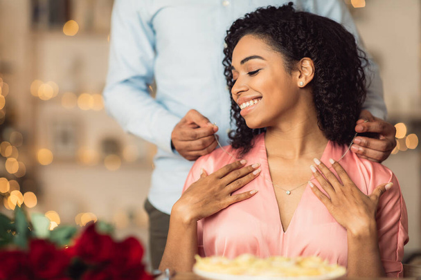 Young black guy wearing necklace on his happy woman - Photo, Image