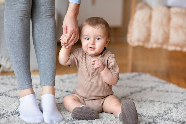 Detailní záběr roztomilé dítě drží mámu za ruku, sedí na podlaze - Fotografie, Obrázek