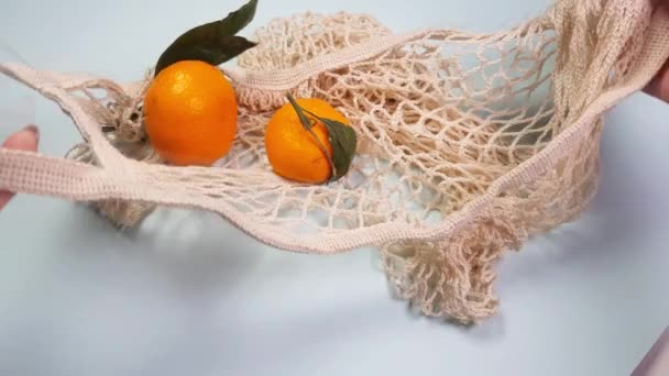 Las mandarinas con hojas verdes se colocan en una bolsa de malla de alimentos reutilizable blanca. Conservación de la naturaleza, concepto de reutilización y reciclaje de productos, concepto de cero residuos, ecológico, consumo razonable, vídeo 4K - Imágenes, Vídeo