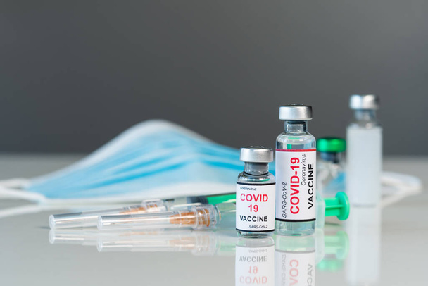 coronavirus covid-19 vaccine bottles and syringe injection medicine and medical mask - 写真・画像