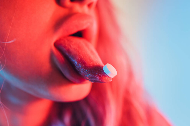 beautiful girl with lsd on tongue in nightclub with pink smoke. - Foto, Imagen