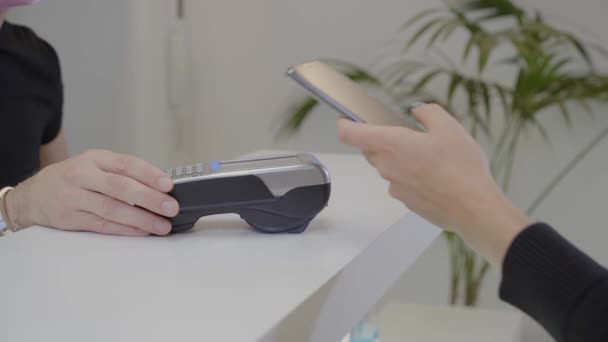 Close-up shot of a client's hands paying with a smartphone in a pharmacy, gynecological, dental or aesthetic clinic. From the customer's point of view. - Footage, Video