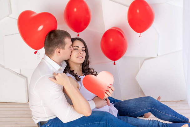 Valentýn, chlap políbí krásnou dívku, která drží velké červené srdce - Fotografie, Obrázek