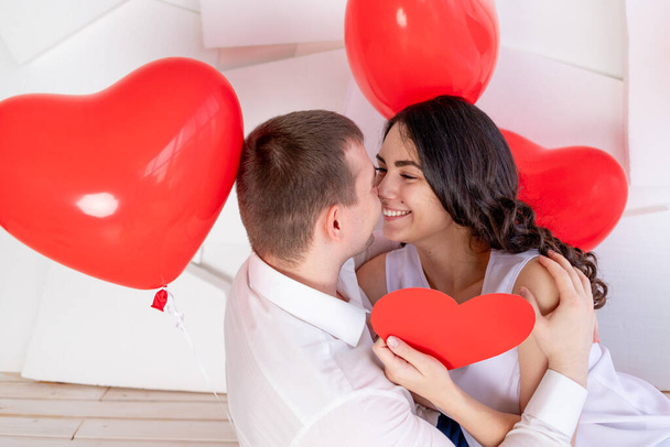 День святого Валентина, парень с красивой девушкой смотрят друг на друга с любящим взглядом, который держит большое красное сердце - Фото, изображение