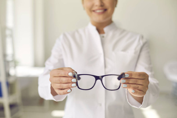 Óptico profesional sonriente dispuesto a ayudarte y pedirte que te pruebes unas gafas nuevas - Foto, imagen