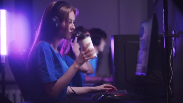 Grupa przyjaciół siedząca w klubie gier i mająca turniej gier online - kobieta pijąca kawę z kubka - Materiał filmowy, wideo