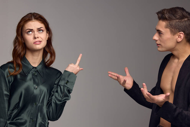 A woman shows her thumb up and a puzzled man gestures with his hands on a gray background - Photo, Image