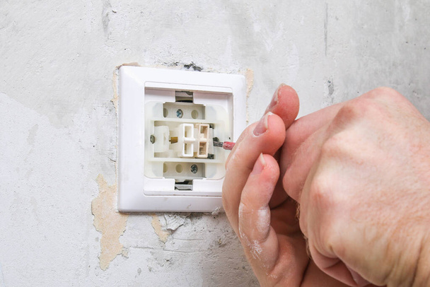 A worker removes light switch for wallpapering. - 写真・画像