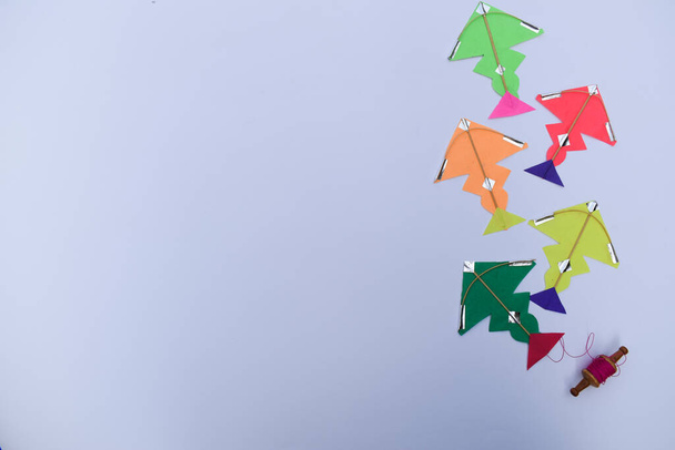 糸巻きの小さなスプールを持つミニチュアの小さな凧、このuttarayan makar sankranti凧揚げの特定のインドの祭りのためのfirki manjhaとパタン。幸せなサンクラントの新年を願うカラフルな凧 - 写真・画像