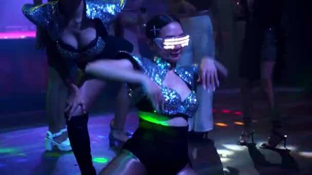 Group of people dance in disco night club to the beat of music from DJ on stage - Footage, Video