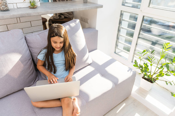 Dziewczynka uczy się online za pomocą laptopa w domu - Zdjęcie, obraz
