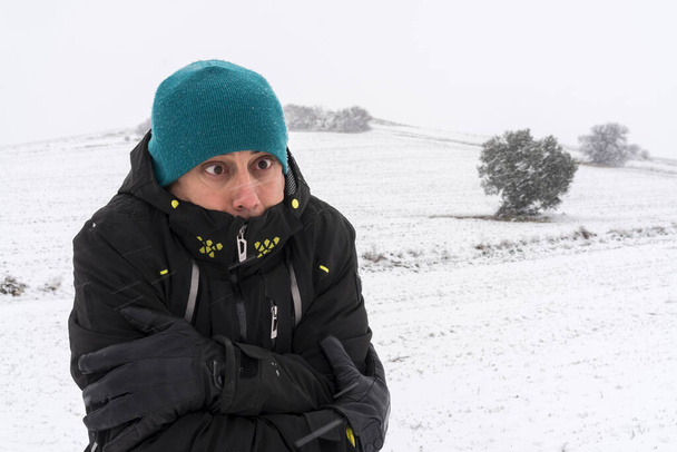 Hombre muy frío con abrigo, sombrero y guantes, en medio de una nevada. España. - Foto, imagen