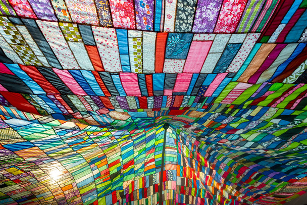Un enorme tejido artístico colorido, hecho de una combinación de piezas de colores de ropa no utilizada y recogida por un sastre. - Foto, imagen