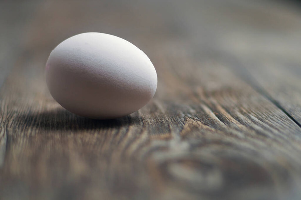 Białe jajko na drewnianym stole, ostrość selektywna - Zdjęcie, obraz