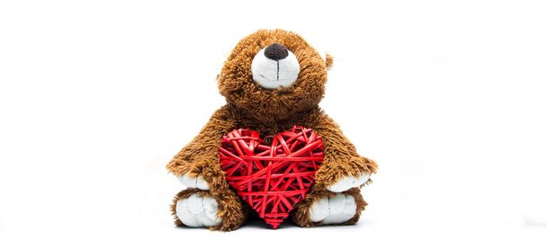 Un oso de juguete sosteniendo un corazón rojo. Sobre fondo blanco. Amor de San Valentín. - Foto, Imagen
