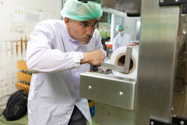 εργάτης αρσενικού εργοστασίου που ελέγχει το ρολό της μηχανής χαρτιού στο εργοστάσιο - Φωτογραφία, εικόνα