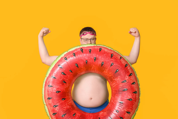 色の背景にインフレータブルリングを持つ太りすぎの男。減量の概念 - 写真・画像