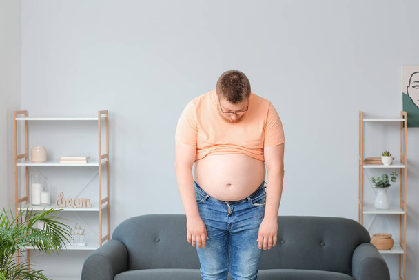 Szomorú túlsúlyos férfi otthon. Fogyás fogalma - Fotó, kép