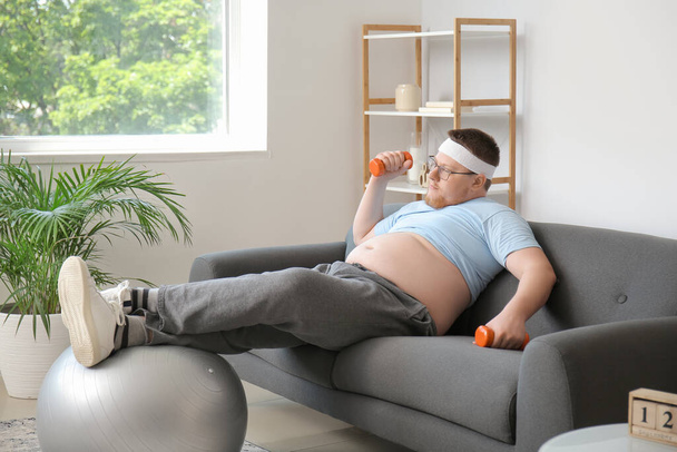 Een man met overgewicht die thuis traint. Gewichtsverlies concept - Foto, afbeelding