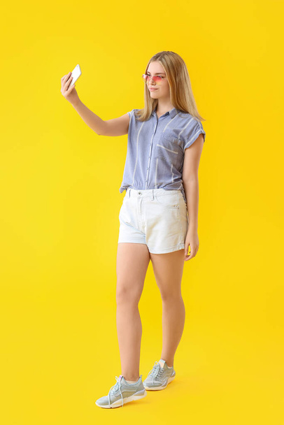Beautiful young woman taking selfie on color background - Foto, afbeelding