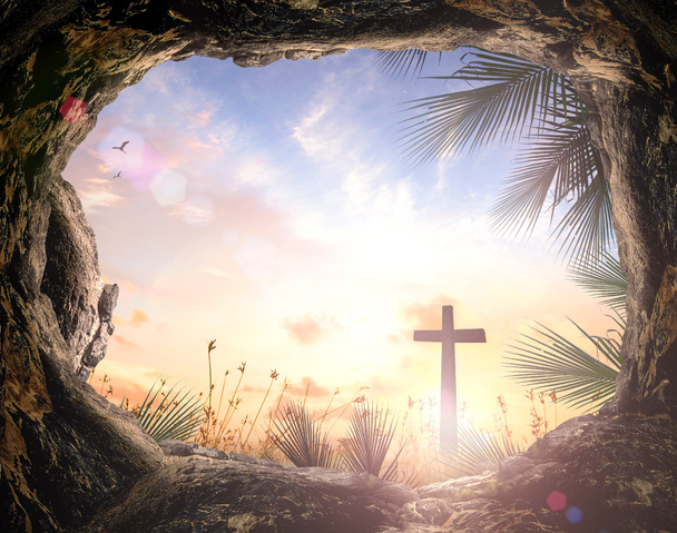 Концепция Вербного воскресенья: Силуэт крест и пустой надгробный камень с пальмовыми листьями на фоне заката луга - Фото, изображение