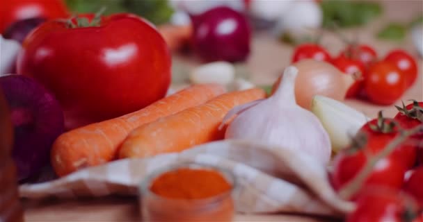 Κοντινό πλάνο των διαφόρων λαχανικών στο τραπέζι Περιστροφή. Νωπές ντομάτες, καρότο, κόκκινο κρεμμύδι και σκόρδο. - Πλάνα, βίντεο