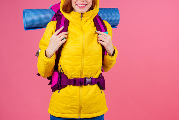 Happy woman ready to hiking in unknown place she is carries big backpack on shoulders in pink studio background - Fotoğraf, Görsel