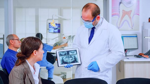 Stomatoloog wijst op digitaal scherm uit te leggen x-ray aan vrouw - Foto, afbeelding
