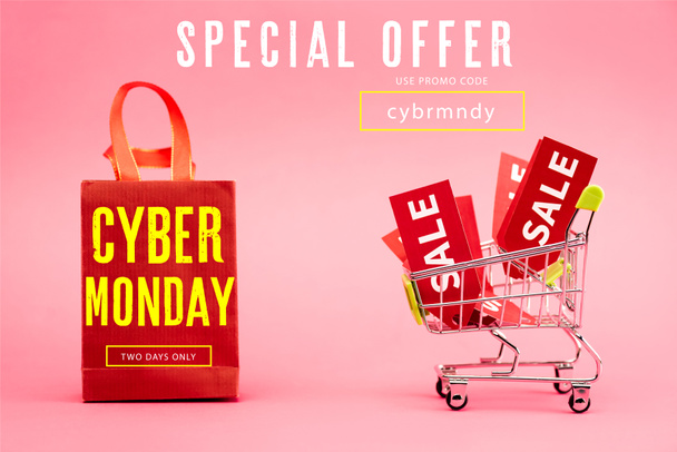 rode tags met verkoop in winkelwagentje in de buurt van papieren tas met cyber maandag belettering op roze - Foto, afbeelding