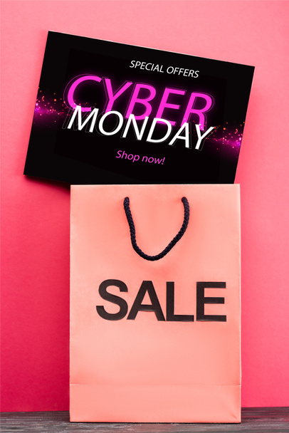 placard with special offers, cyber monday lettering near shopping bag on pink - Fotó, kép