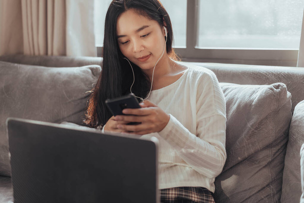 Young woman using smartphone and sitting at home. Beautiful businesswoman using mobile phone while working at home. Working at home  during Coronavirus or Covid-19 quarantine. - Foto, Imagem
