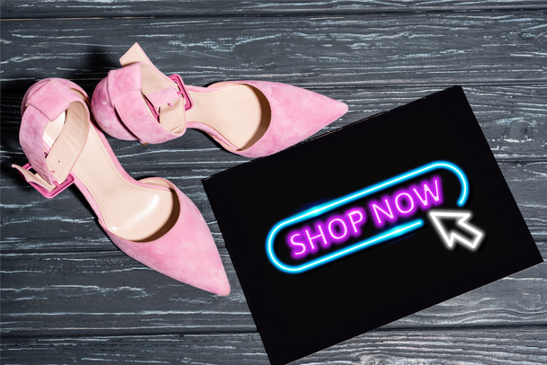 vista superior de zapatos de color rosa cerca de la pancarta con neón tienda ahora letras en la superficie de madera - Foto, imagen