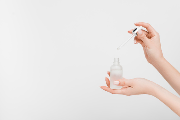 cropped view of woman holding bottle with serum and pipette isolated on white - Fotó, kép