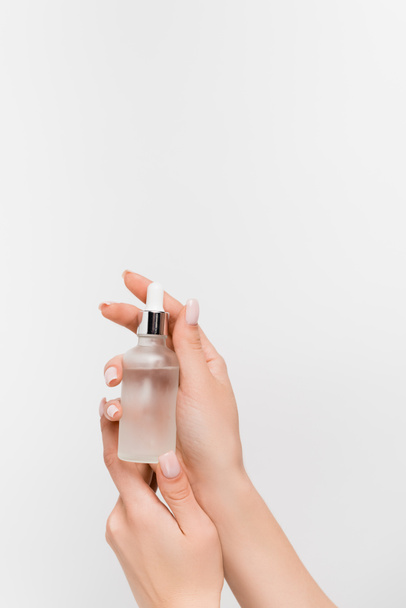 bijgesneden zicht op vrouw met fles met serum geïsoleerd op wit - Foto, afbeelding