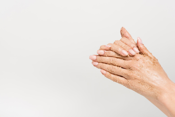 vista parcial de la mujer aplicando exfoliante en las manos aisladas en blanco - Foto, Imagen