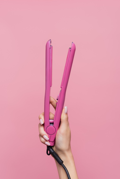 cropped view of woman holding hair straightener isolated on pink - Photo, image