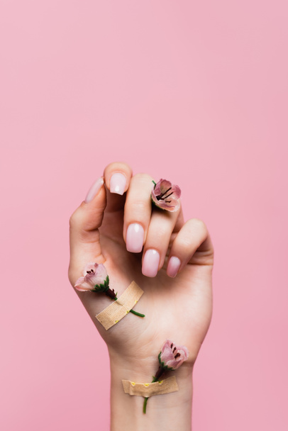 επίδεσμοι με λουλούδια στο γυναικείο χέρι απομονωμένοι σε ροζ - Φωτογραφία, εικόνα