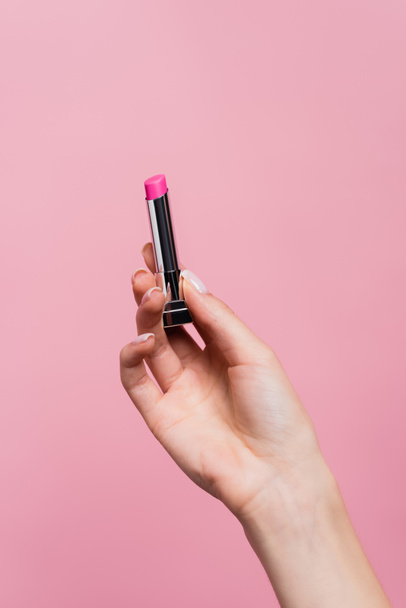 cropped view of woman holding lipstick in hand isolated on pink - Foto, Imagem