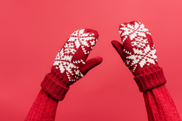 cropped view of female hands in warm mittens isolated on red - Foto, afbeelding