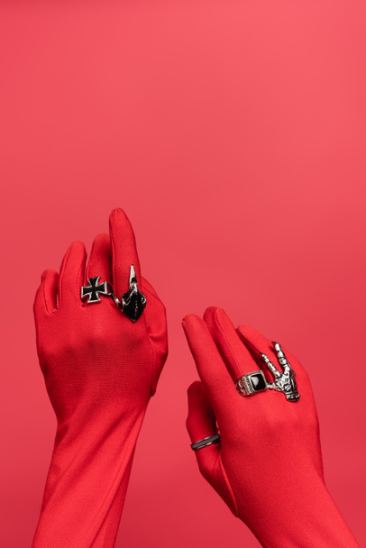 partial view of female hands in gloves with rings isolated on red - Foto, afbeelding