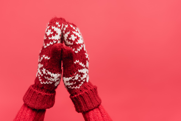 cropped view of female praying hands in warm mittens isolated on red - Foto, afbeelding