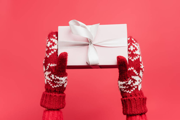 cropped view of woman in mittens holding gift box isolated on red - Photo, Image