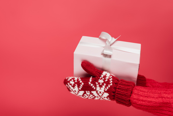 cropped view of woman in mittens holding present isolated on red - Photo, Image
