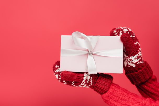 cropped view of woman in mittens holding wrapped present isolated on red - Photo, Image