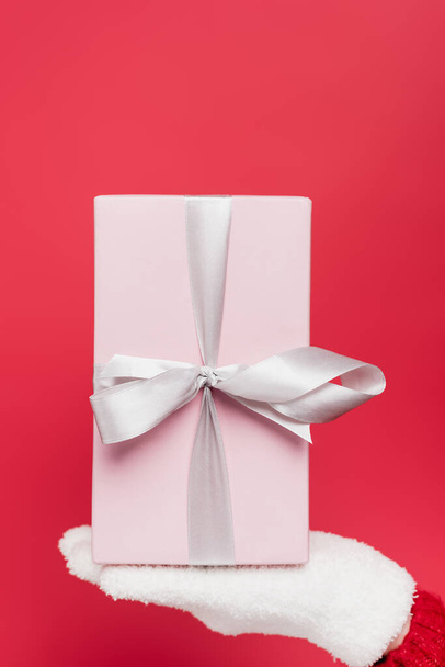 cropped view of woman in white glove holding pink present isolated on red - Foto, Imagem