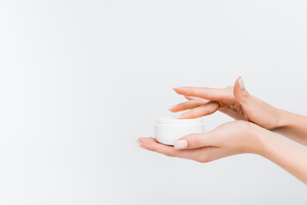 partial view of woman holding jar and applying cosmetic cream isolated on white - Photo, image