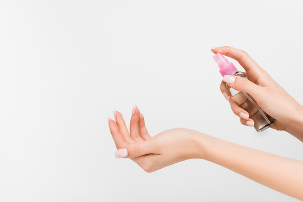 cropped view of woman holding spray bottle with liquid isolated on white - Fotó, kép