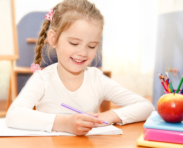 Cute little girl is writing at the desk  in preschool - Fotografie, Obrázek